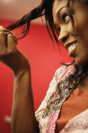 Side view of woman looking at her hairの写真素材