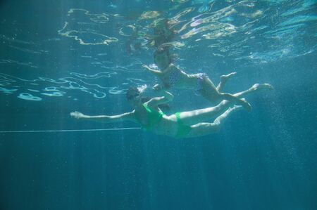 Mother and daughter in swimming pool under waterの写真素材