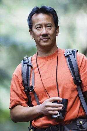 Portrait of man holding binoculars while hikingの写真素材