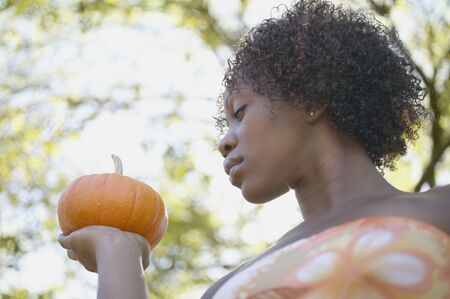Low angle portrait of woman holding pumpkinの写真素材