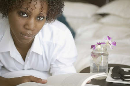 Portrait of woman on bed reading book