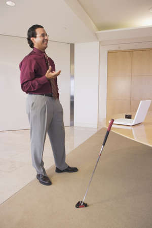 Businessman standing in office with golf club