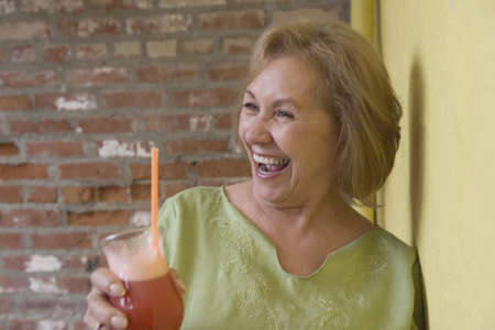 Woman holding drink and laughingの写真素材