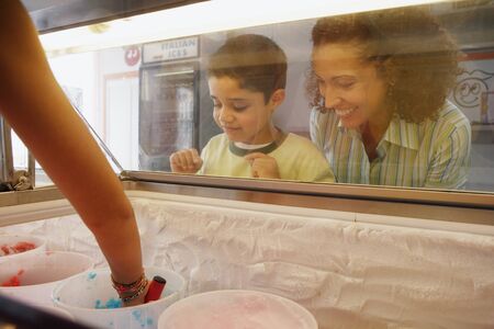 Mother and son watching through ice cream case windowの写真素材