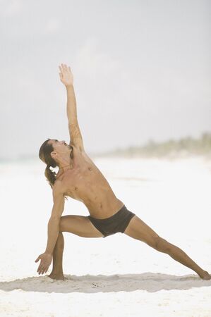 Young man doing yoga on the beachの写真素材