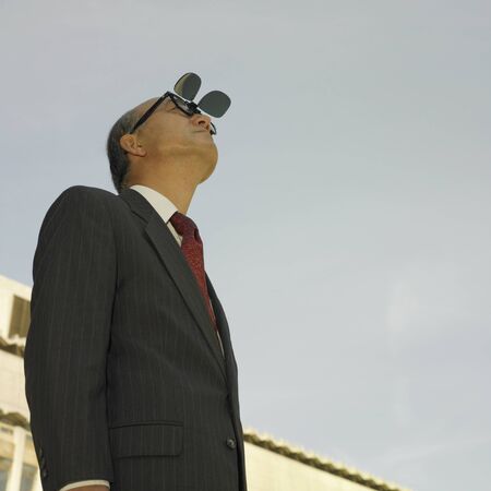 Low angle view of businessman looking at sky with sunglasses