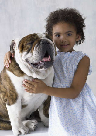 Portrait of young girl hugging bulldogの写真素材