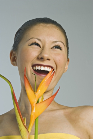 Young woman smiling and holding an exotic flowerの写真素材