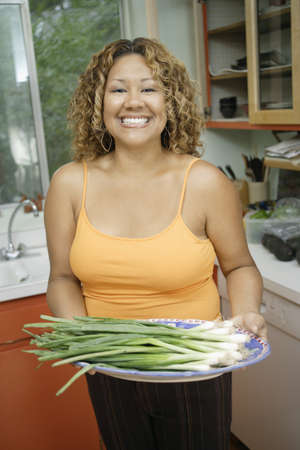 Young woman holding a plate of spring onionsの写真素材