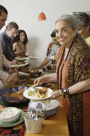 Middle-aged woman holding a plate of foodの写真素材