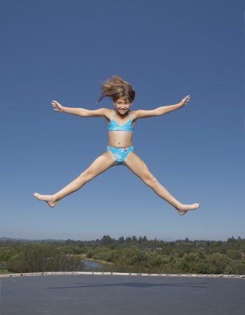 Young girl jumping on a trampolineの写真素材