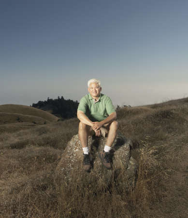Senior man posing for the camera on a rockの写真素材