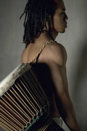Young man carrying a drum on his backの写真素材