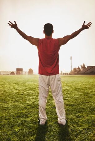 Male athlete holding his arms out on football fieldの写真素材