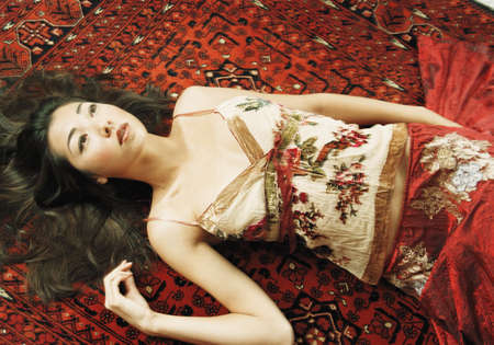 Young woman lying on the carpetの写真素材