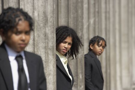 Students hiding behind stone pillarsの写真素材