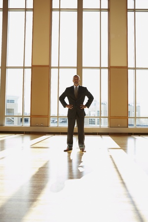 Businessman standing in sunlit room with hands on his hips, North Bethesda, Maryland, United Statesの写真素材