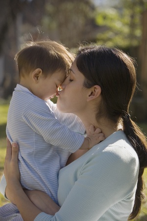 Hispanic mother kissing baby outdoorsの写真素材