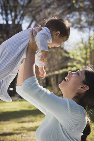 Hispanic mother holding baby up outdoors