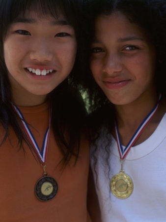 Portrait of two girls smiling with metals around neckの写真素材
