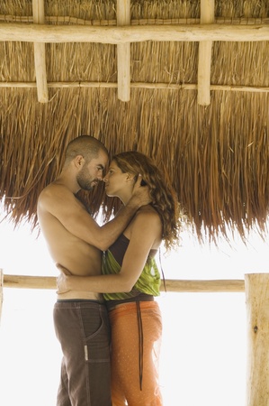 Couple kissing underneath thatch roofの写真素材