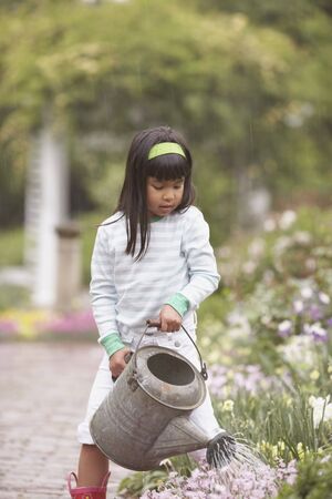 Asian girl using watering can in gardenの写真素材