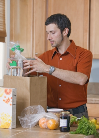 Man unpacking groceries in kitchenの写真素材