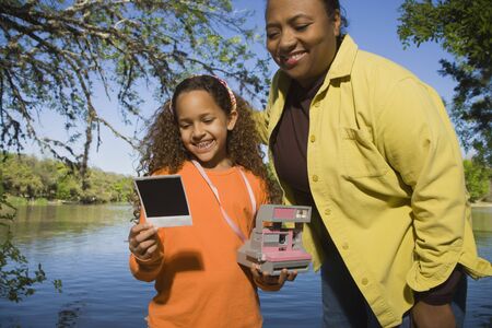 African mother and daughter looking at photograph outdoorsの写真素材