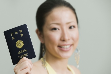 Asian woman smiling and holding passportの写真素材