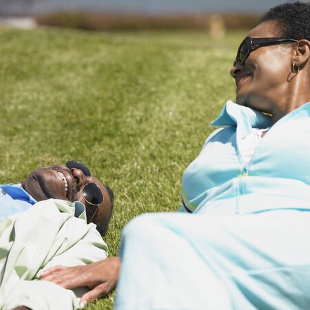 Senior African couple laying in grass smilingの写真素材