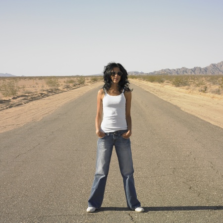 Woman standing in middle of deserted roadの写真素材