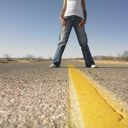 Surface shot of woman standing in middle of deserted roadの写真素材