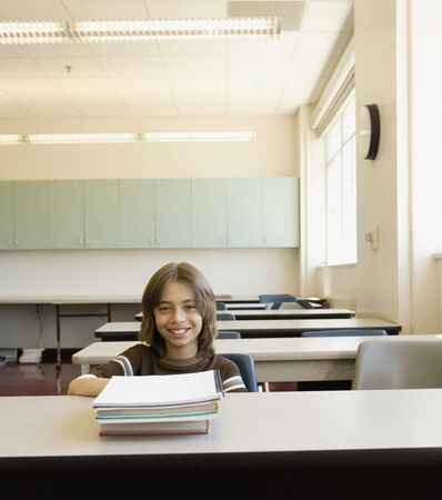 Boy sitting at desk in empty classroomの写真素材