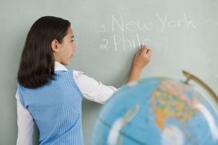 Hispanic girl writing on blackboardの写真素材