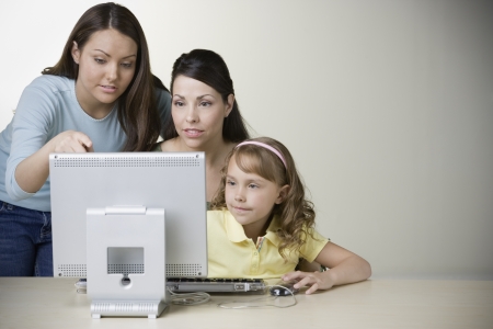 Hispanic mother and daughters working on computerの写真素材