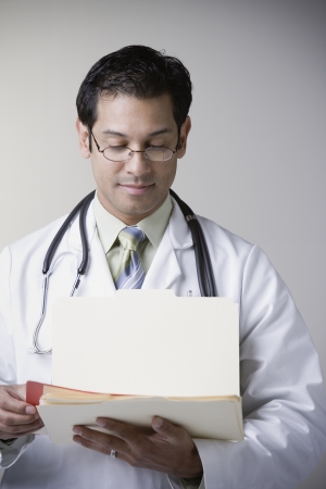 Hispanic male doctor reading fileの写真素材
