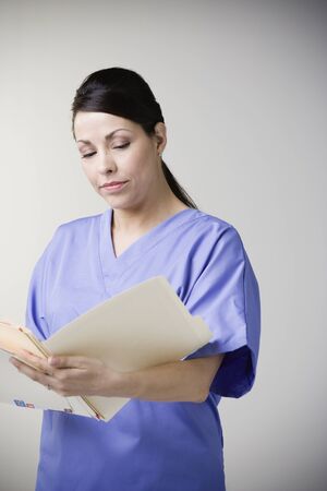 Hispanic female nurse reading fileの写真素材