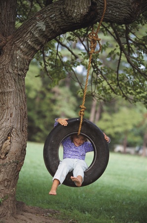 Young girl sitting in tire swingの写真素材