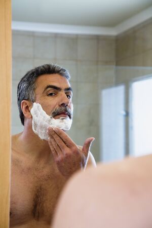 Middle-aged Hispanic man applying shaving creamの写真素材