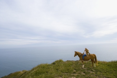 Senior woman horse riding bareback on cliffの写真素材