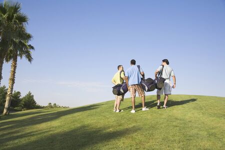 Three men walking on golf courseの写真素材