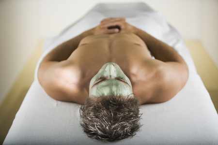 Man laying on spa table with facial treatmentの写真素材