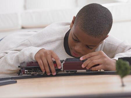 African boy playing with model train on floorの写真素材