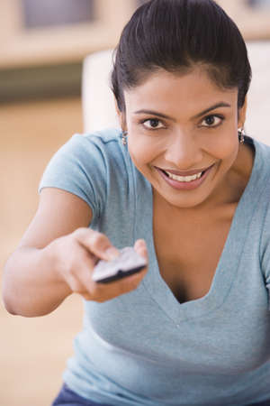Indian woman changing channel with remote controlの写真素材