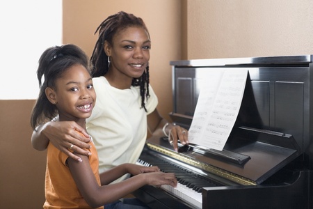 African mother helping daughter with piano lessonsの写真素材