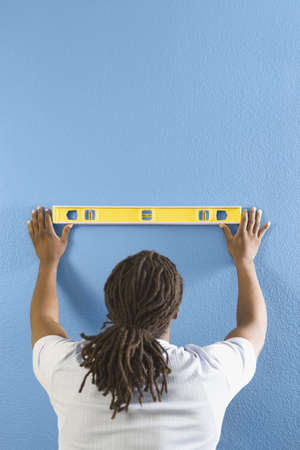 Rear view of African man using level on wallの写真素材