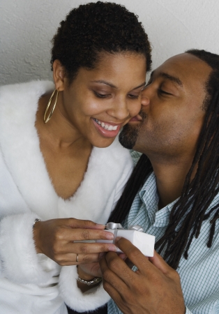 African couple exchanging gift and kissingの写真素材