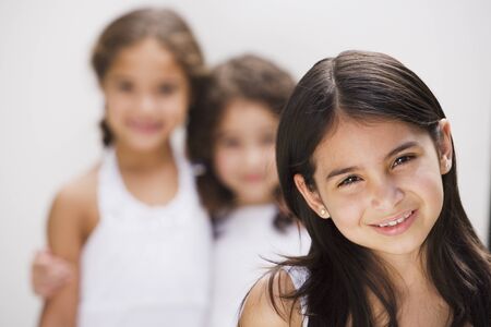 Hispanic girl smiling with sisters in backgroundの写真素材