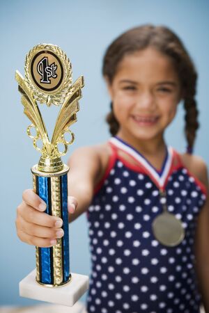 Hispanic girl holding medal and trophyの写真素材