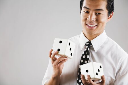 Portrait of Asian man holding diceの写真素材